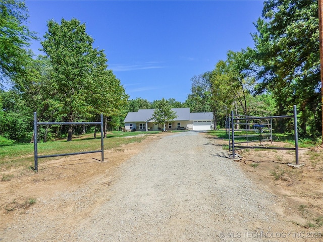 414467 E 1090th Rd, Checotah, OK 74426 - single story home with dirt driveway, view of wooded area, and an attached garage