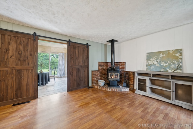 18005 S 4185th Rd, Claremore, OK 74017 - living area with wood finished floors, a barn door, a textured ceiling, a wood stove, and wood walls