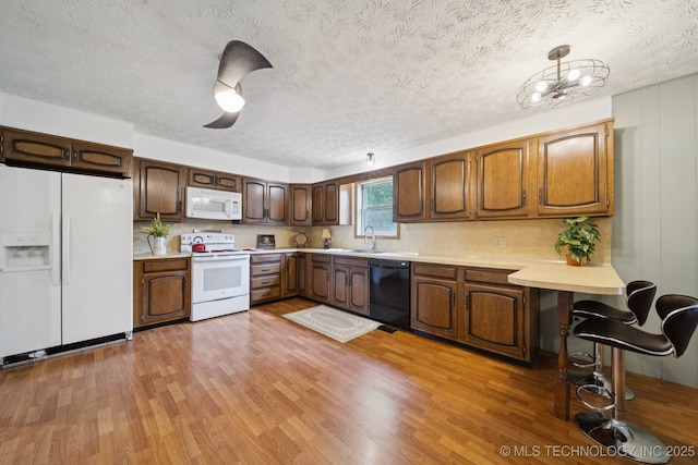18005 S 4185th Rd, Claremore, OK 74017 - kitchen featuring white appliances, a textured ceiling, light countertops, light wood-type flooring, and backsplash