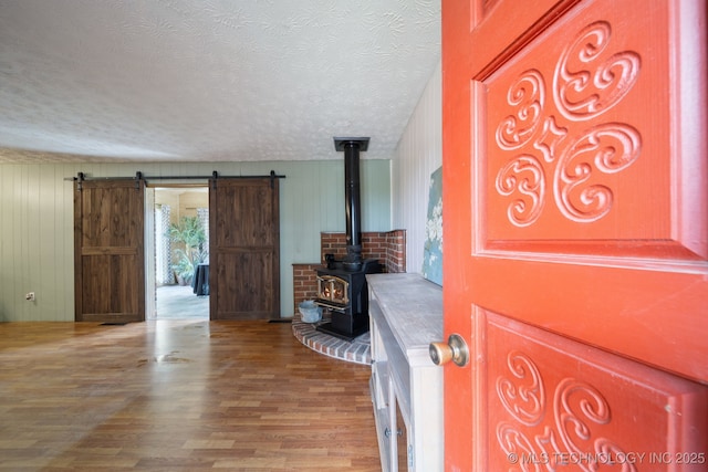 18005 S 4185th Rd, Claremore, OK 74017 - unfurnished living room with a textured ceiling, wood finished floors, a barn door, a wood stove, and wood walls