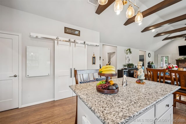 2402 W Kingsport Ct S, Broken Arrow, OK 74011 - kitchen featuring wood finished floors, a barn door, white cabinets, open floor plan, and light stone countertops