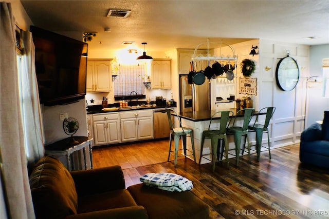 330 Kiamichi, Eufaula, OK 74432 - kitchen featuring appliances with stainless steel finishes, dark countertops, dark wood-style floors, a kitchen bar, and a kitchen island
