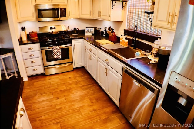 330 Kiamichi, Eufaula, OK 74432 - kitchen with stainless steel appliances, dark countertops, light wood-style floors, and white cabinets