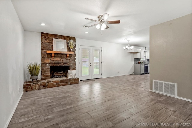 30078 E 143rd St S, Coweta, OK 74429 - unfurnished living room featuring ceiling fan, a stone fireplace, a chandelier, and wood finished floors