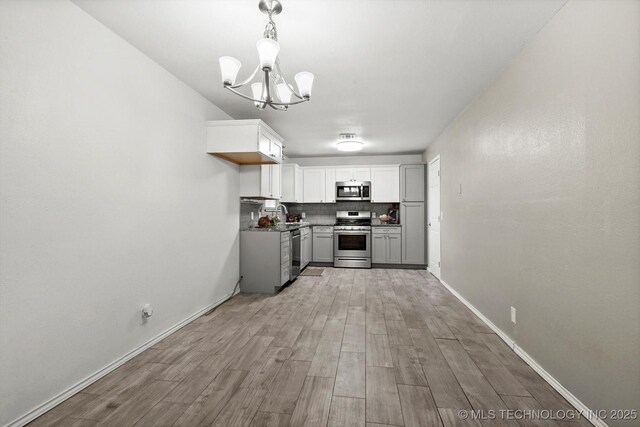 30078 E 143rd St S, Coweta, OK 74429 - kitchen with appliances with stainless steel finishes, a chandelier, light wood-style floors, decorative light fixtures, and decorative backsplash
