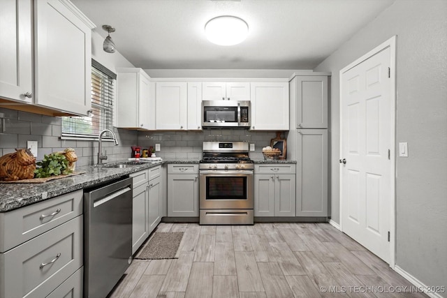 30078 E 143rd St S, Coweta, OK 74429 - kitchen with stainless steel appliances, decorative backsplash, dark stone countertops, light wood-style floors, and gray cabinetry