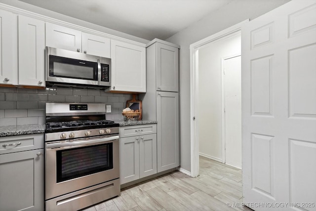 30078 E 143rd St S, Coweta, OK 74429 - kitchen featuring stainless steel appliances, decorative backsplash, stone countertops, light wood-style flooring, and white cabinets