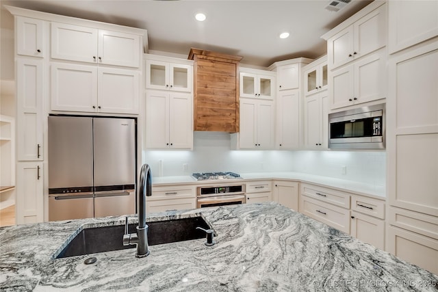 6904 E 86th Pl N, Owasso, OK 74055 - kitchen with appliances with stainless steel finishes, white cabinets, glass insert cabinets, decorative backsplash, and recessed lighting