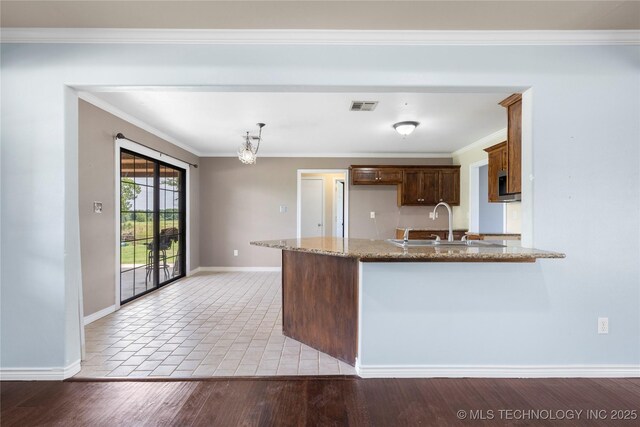 5764 S Carr, Pen, OK 74525 - kitchen with a peninsula, light stone counters, ornamental molding, a chandelier, and wood finished floors