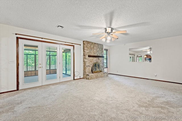 1020 Lariat Dr, Bartlesville, OK 74006 - unfurnished living room featuring a ceiling fan, french doors, carpet floors, a textured ceiling, and a fireplace