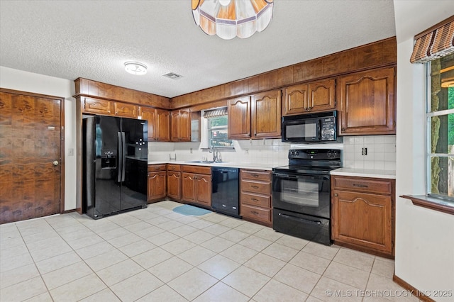 1020 Lariat Dr, Bartlesville, OK 74006 - kitchen featuring black appliances, a textured ceiling, tasteful backsplash, brown cabinets, and light countertops