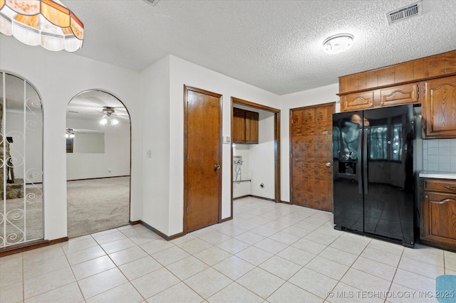 1020 Lariat Dr, Bartlesville, OK 74006 - kitchen with black refrigerator with ice dispenser, a textured ceiling, ceiling fan, light tile patterned flooring, and light countertops