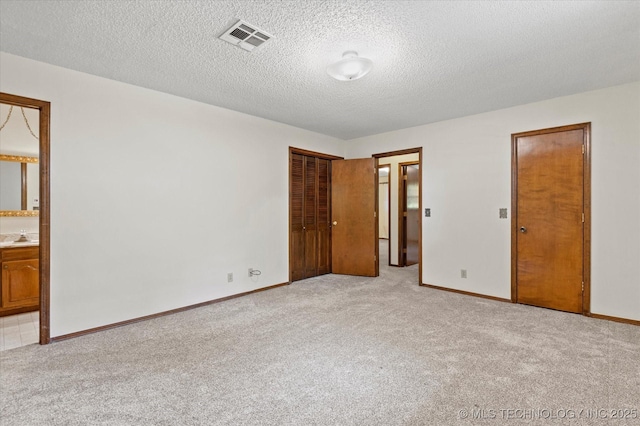 1020 Lariat Dr, Bartlesville, OK 74006 - unfurnished bedroom with light colored carpet, a textured ceiling, and ensuite bathroom