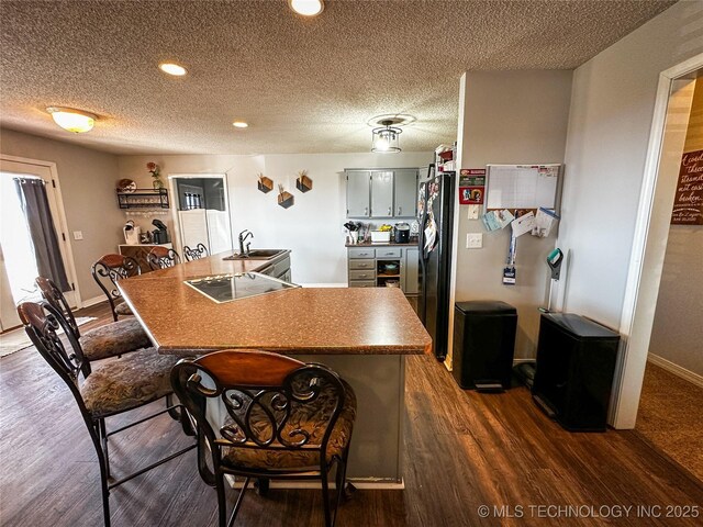438505 E 370th Rd, Adair, OK 74330 - kitchen featuring electric stovetop, dark wood-style floors, black refrigerator with ice dispenser, a textured ceiling, and a breakfast bar