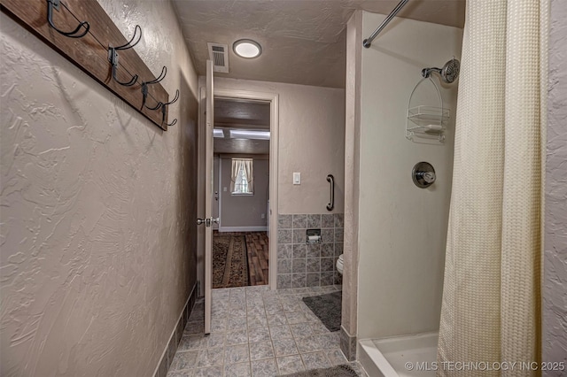 2676 Masters, Sulphur, OK 73086 - bathroom featuring a shower with curtain, a textured ceiling, tile walls, and a textured wall