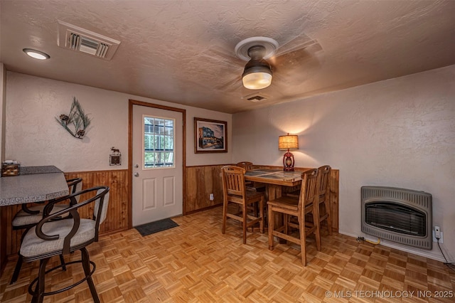 2676 Masters, Sulphur, OK 73086 - dining room featuring heating unit, a textured ceiling, wainscoting, wood walls, and ceiling fan