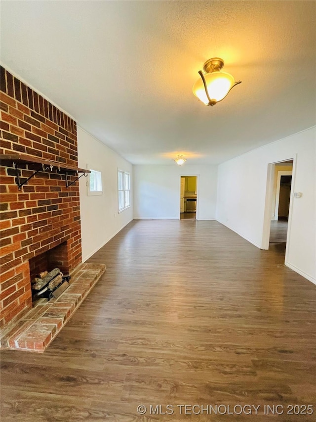 910 N Collins St, Okmulgee, OK 74447 - unfurnished living room with wood finished floors, a brick fireplace, and a textured ceiling