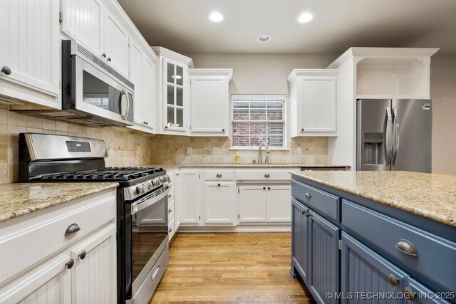 9929 S 85th E Ave, Tulsa, OK 74133 - kitchen featuring appliances with stainless steel finishes, white cabinetry, blue cabinetry, tasteful backsplash, and recessed lighting