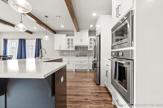 14271 S College Ave, Bixby, OK 74008 - kitchen featuring stainless steel appliances, dark wood finished floors, beamed ceiling, tasteful backsplash, and light countertops