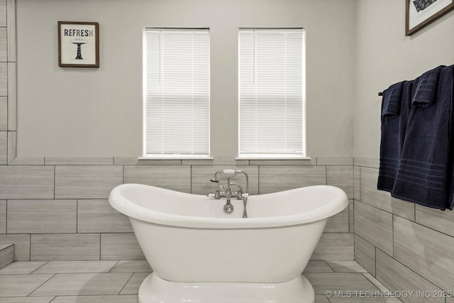 14271 S College Ave, Bixby, OK 74008 - bathroom with tile walls, a soaking tub, wainscoting, and tile patterned floors