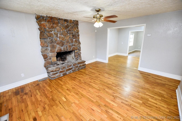 1107 Hillcrest Ave, Tahlequah, OK 74464 - unfurnished living room featuring a ceiling fan, wood-type flooring, a textured ceiling, and a fireplace