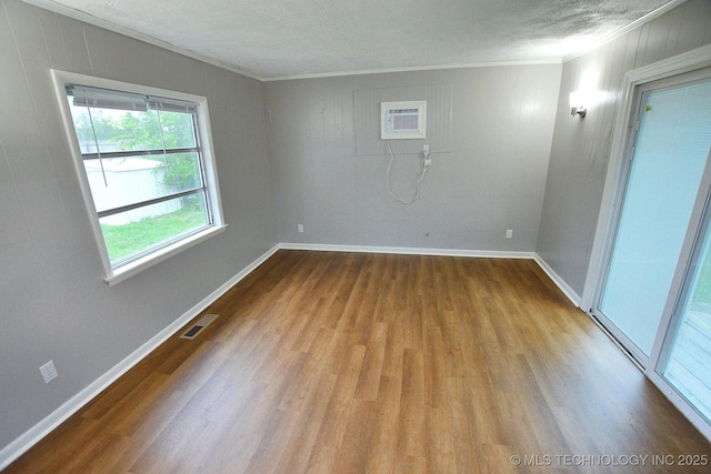 1107 Hillcrest Ave, Tahlequah, OK 74464 - spare room with wood finished floors, crown molding, a wall mounted AC, and a textured ceiling