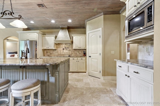 9312 N 93rd Ave E, Owasso, OK 74055 - kitchen with custom range hood, stainless steel appliances, arched walkways, wooden ceiling, and backsplash