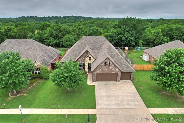 9312 N 93rd Ave E, Owasso, OK 74055 - view of front of house featuring driveway, a garage, a wooded view, and stone siding