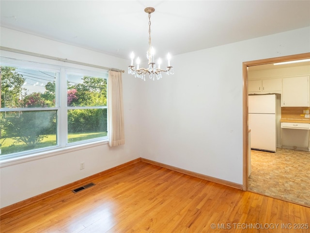 1508 E Seminole Ave, Mcalester, OK 74501 - empty room with a chandelier and light wood-style flooring