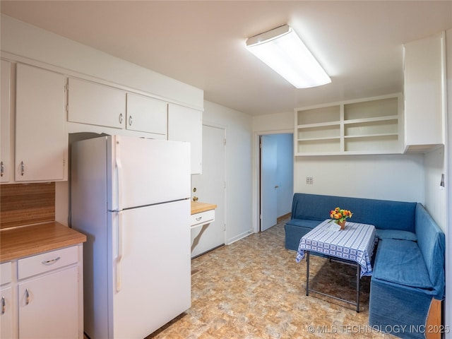 1508 E Seminole Ave, Mcalester, OK 74501 - kitchen with freestanding refrigerator, open shelves, white cabinetry, light flooring, and light countertops