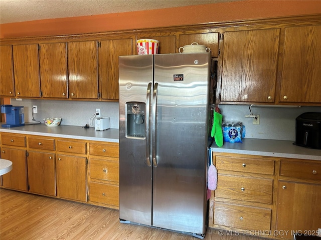 1203 NW 5th St, Stigler, OK 74462 - kitchen featuring stainless steel fridge, brown cabinetry, light wood finished floors, and light countertops
