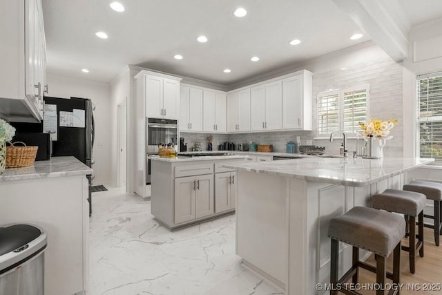 9703 S 100th E Ave, Tulsa, OK 74133 - kitchen featuring double oven, recessed lighting, backsplash, a peninsula, and a kitchen breakfast bar
