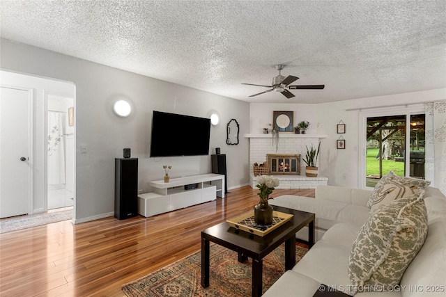 4504 S Cedar Ave, Broken Arrow, OK 74011 - living room featuring a ceiling fan, wood finished floors, a textured ceiling, and a fireplace