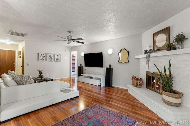 4504 S Cedar Ave, Broken Arrow, OK 74011 - living area featuring wood finished floors, a textured ceiling, ceiling fan, and a brick fireplace