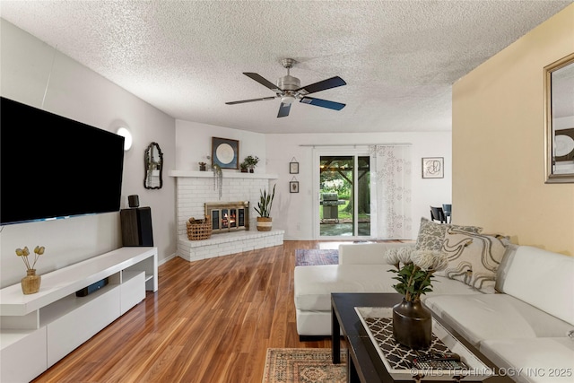 4504 S Cedar Ave, Broken Arrow, OK 74011 - living room featuring a textured ceiling, ceiling fan, wood finished floors, and a brick fireplace