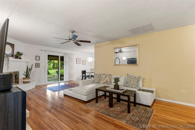 4504 S Cedar Ave, Broken Arrow, OK 74011 - living room featuring a textured ceiling, a ceiling fan, wood finished floors, a chandelier, and a wood stove