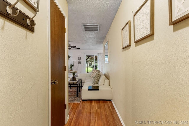 4504 S Cedar Ave, Broken Arrow, OK 74011 - corridor featuring a textured ceiling, a textured wall, and wood finished floors