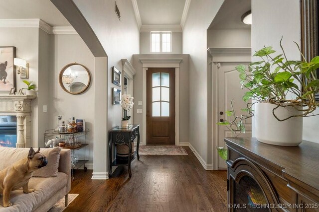 9402 E 109th St S, Tulsa, OK 74133 - foyer entrance featuring dark wood-style flooring, crown molding, arched walkways, and a premium fireplace