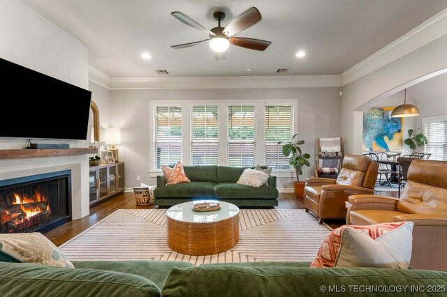 9402 E 109th St S, Tulsa, OK 74133 - living area with ornamental molding, plenty of natural light, a ceiling fan, a warm lit fireplace, and wood finished floors