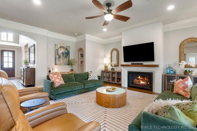 9402 E 109th St S, Tulsa, OK 74133 - living room featuring arched walkways, a warm lit fireplace, wood finished floors, a ceiling fan, and recessed lighting