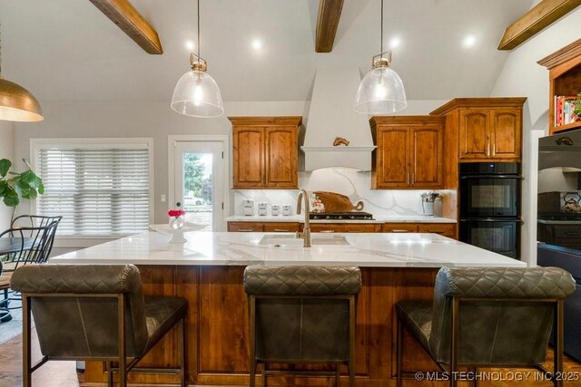 9402 E 109th St S, Tulsa, OK 74133 - kitchen with custom exhaust hood, a center island with sink, decorative light fixtures, and brown cabinetry