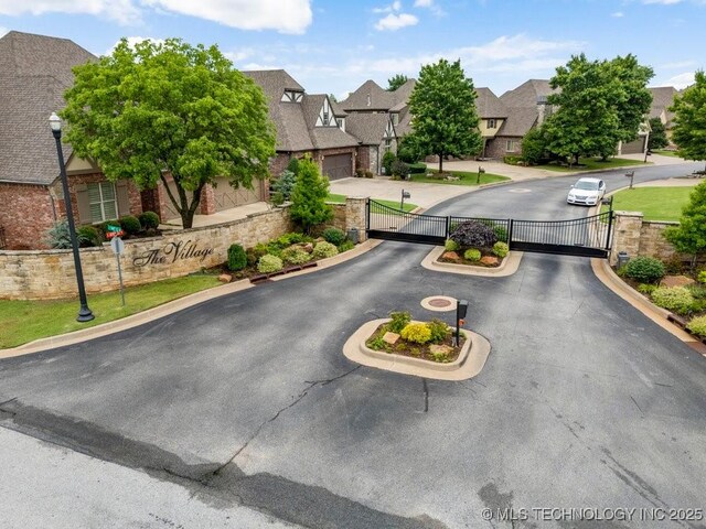 9402 E 109th St S, Tulsa, OK 74133 - view of asphalt street with a gate, a residential view, curbs, a gated entry, and street lights