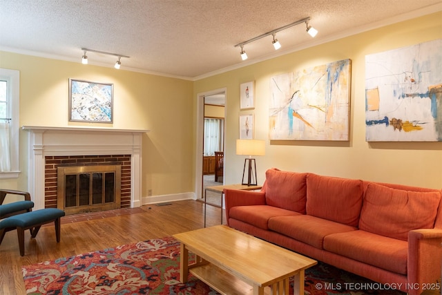 3524 E 12th Pl, Tulsa, OK 74112 - living room featuring rail lighting, wood finished floors, a textured ceiling, crown molding, and a brick fireplace