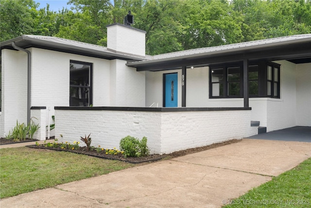 575 N 7th St, Muskogee, OK 74401 - view of front of home featuring brick siding, a chimney, and a metal roof