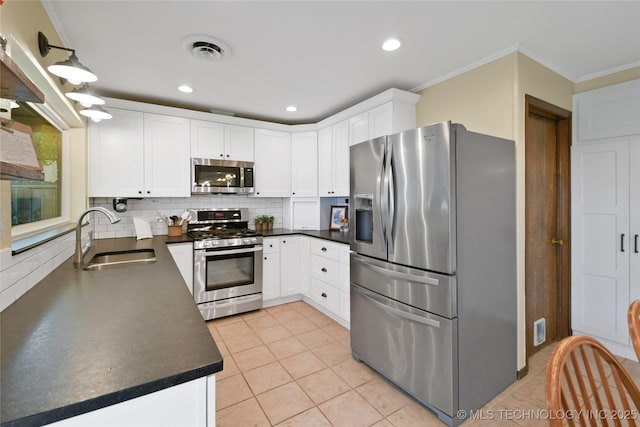 1900 10th Ave NW, Ardmore, OK 73401 - kitchen with stainless steel appliances, dark countertops, decorative backsplash, white cabinetry, and crown molding