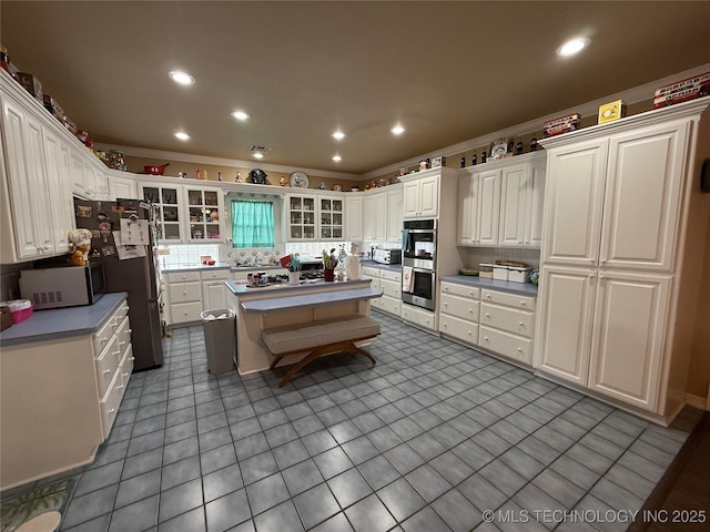 607 Nelson, Mcalester, OK 74501 - kitchen with stainless steel appliances, a center island, white cabinetry, glass insert cabinets, and crown molding