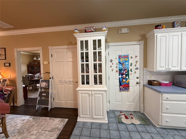 607 Nelson, Mcalester, OK 74501 - kitchen with white cabinetry, ornamental molding, glass insert cabinets, tasteful backsplash, and dark tile patterned flooring