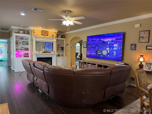 607 Nelson, Mcalester, OK 74501 - living area with arched walkways, dark wood-style floors, a ceiling fan, crown molding, and a tile fireplace