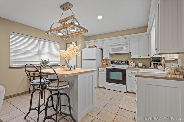 1604 9th Ave NW, Ardmore, OK 73401 - kitchen featuring white appliances, wood counters, light tile patterned floors, white cabinets, and a kitchen bar