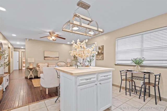 1604 9th Ave NW, Ardmore, OK 73401 - kitchen with ceiling fan, wood counters, white cabinets, light tile patterned floors, and a breakfast bar area